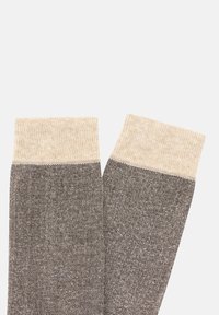 Grå och beige strukturerade knästrumpor med en kontrasterande ljusbeige ribbad kant, prydda med en finstickad mönstring över hela kroppen.