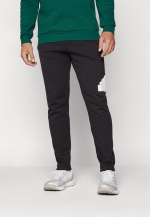 Pantalones de chándal negros hechos de una mezcla de algodón, con un ajuste slim, cintura elástica y un logo blanco en el muslo izquierdo.