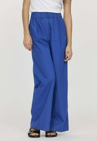 Pantalons larges bleus avec une taille élastique, fabriqués à partir d'un tissu léger, offrant une texture lisse et une coupe décontractée.