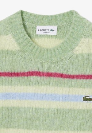 Maglione a righe verde e crema con bande rosse e blu; caratteristiche di un collo a girocoscia a costine; logo Lacoste sul lato sinistro. Texture a maglia morbida.