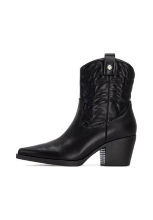 Botas de cowboy de cuero negro con punta afilada, patrón floral en relieve en la caña y un tacón grueso y a rayas. Presenta una lengüeta para facilitar su puesta.