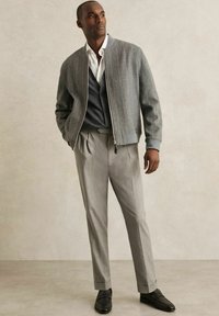 Gray bomber jacket over a dark gray cardigan, paired with light gray trousers. Black loafers complete the look. Simple design and tailored fit.