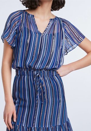 Robe bleue à rayures en tissu léger, avec des manches courtes et volantées, un décolleté en V, une taille cintrée et un ourlet à volants. Présente des accents métalliques.