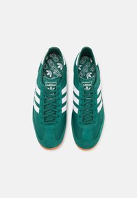 Gröna mockasneakers med vita ränder, med snörningsdesign och ett mönstrat innersula. Gummisula för bra grepp.