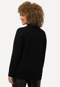 Schwarze Strickjacke mit lockerer Passform, lange Ärmel, runder Ausschnitt und dezenten Rippakzenten am Saum und an den Bündchen.