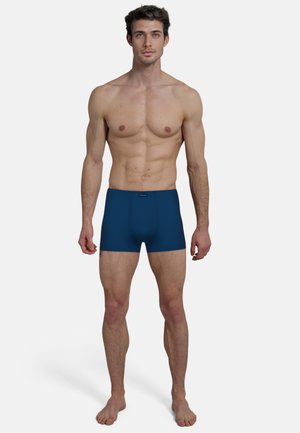 Boxers bleus marine avec une surface texturée, une taille élastique et un branding minimal. Conçus pour un ajustement snug et confortable.