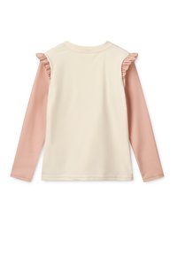 Langermet topp med en kremet beige kropp, lyserøde ermer og volanger på skuldrene. Glatt tekstur, enkelt design.