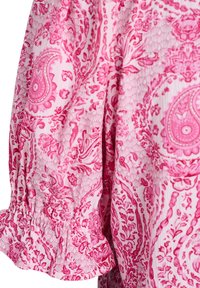 Tissu à motif floral cachemire rose et blanc avec un détail de volants froncés le long du bord d'une manche de vêtement.