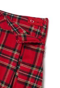 Tissu tartan rouge présentant des sections avec des lignes noires, jaunes et blanches. Comprend une fermeture à bouton et une fermeture éclair sur le côté.