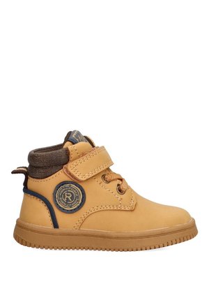 Bota de tobillo de cuero color marrón claro con un acento de tela marrón, correa de velcro y parche de logo circular en el lateral. Suela de goma con agarre texturizado.