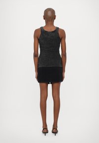 Svart ribbestrikket tanktop med en tettsittende design, kombinert med et svart denim mini-skjørt og hælesandaler. Glatt tekstur og minimal detaljering.
