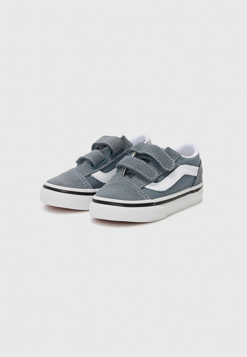 Grijze canvas sneakers met klittenbandsluitingen, witte accenten, zwarte rand en een rubberen zool. Heeft dubbele stiksels en een gewatteerde binnenkant.
