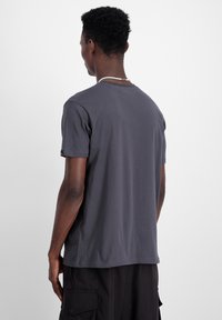 Siva, kratki rukav majica od mekanog pamuka, s okruglim izrezom i opuštenim krojem, prikazana straga. Nema vidljivih uzoraka ili detalja.