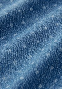 Denim-kangasta vaaleasta keskitumman sinisestä sävystä, jossa on hienovarainen tekstuurikuvio ja pehmeä, hieman haalistunut ilme.