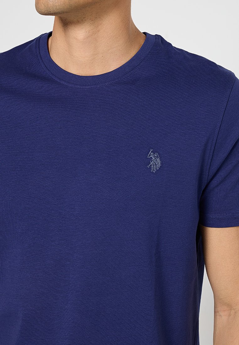Marineblaues Rundhals-T-Shirt aus Baumwolle. Hat kurze Ärmel und ein kleines gesticktes Logo auf der linken Brust. Glatte Textur.