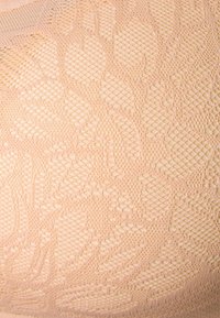 Tissu tricoté rose clair présentant un motif floral texturé avec des détails entrelacés, offrant une apparence douce et tactile.