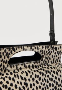 Κοντινή λήψη τσάντας με σχέδιο λεοπάρδαλης, με μαύρο δερμάτινο λουράκι και οβάλ λαβή με κοπή.