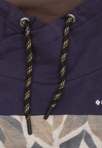 Hoodie met een paarse bovenkant, een bruine nek en een gegarandeerde onderkant versierd met bladeren in beige en grijs. Zwarte trekkoorden met gele accenten.