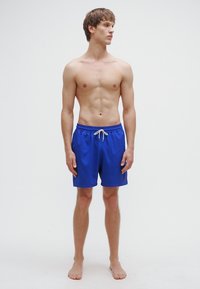 Μπλε μαγιό σορτς από ελαφρύ ύφασμα, με ελαστική ζώνη μέσης και κορδόνι. Λεπτή υφή, μήκος μέχρι το γόνατο.