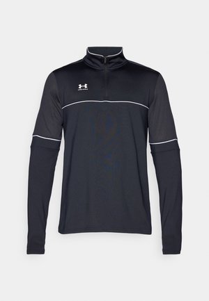 Haut à manches longues noir avec zip quart et accents blancs, portant le logo Under Armour sur la poitrine supérieure gauche, fabriqué dans un tissu lisse et extensible.