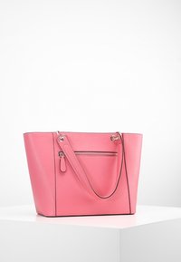 Różowa skórzana torba typu tote o teksturowanym wykończeniu, z dwoma okrągłymi uchwytami i zewnętrzną kieszenią zapinaną na zamek. Kontrastowe czarne akcenty.