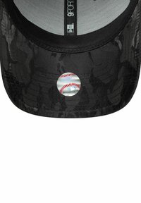 Schwarze Camouflage-Baseballkappe mit einem silbernen runden Aufnäher, auf dem eine Baseballgrafik abgebildet ist. Glattes Material, flacher Schirm und Belüftungslöcher.