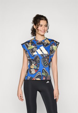 Blue short-sleeve top with a butterfly print, featuring a round neckline and textured, structured shoulders. Black leggings with subtle branding.
