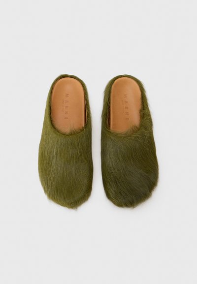 Gröna skinnslip-on skor med rund tå och mjuk textur. Läderinlägg med prägad varunamn. Ingen synlig hårdvara eller accenter.