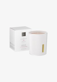 Doftljus i en räfflad vit keramikbehållare med guldaccent. Åtföljs av en kvadratisk vit låda. Doft: rismjölk och körsbärsblomma.