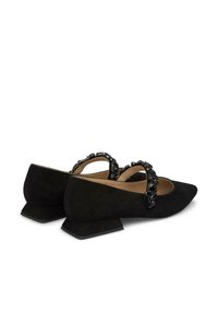 Zapatos planos de ante negro con punta afilada y un pequeño tacón cuadrado, que presentan una tira decorativa de cuentas negras cruzando el empeine.