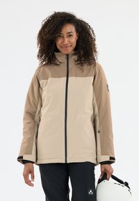 Tan og brun vandtæt jakke med h�øj krave, lynlås foran og sorte detaljer; kombineret med sorte bukser og en hvid hjelm.