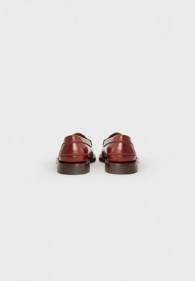 Braune Lederschuhe mit glatter Oberfläche, ausgestattet mit einer abgerundeten Zehenpartie und einer niedrigen, flachen Sohle. Das Design umfasst feine Steppnähte.