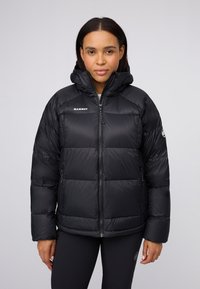 Doudoune noire avec capuche, ornée de coussinets horizontaux, d'une fermeture éclair intégrale, de poches latérales et du logo de la marque sur la poitrine et la manche.