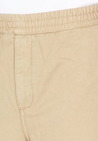 Beige lightweight pants featuring an elastic waistband, side pocket, and smooth, textured fabric. Suitable for casual wear.