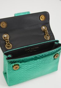 Borsa a tracolla in pelle verde con stampa serpente, dotata di un interno nero, hardware dorato, dettaglio a catena e chiusura a scatto.