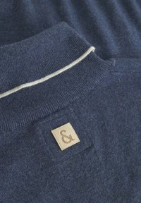 Maglione blu navy con lavorazione a maglia testurizzata, caratterizzato da una striscia crema a contrasto sul colletto e un piccolo etichetta in pelle rettangolare.