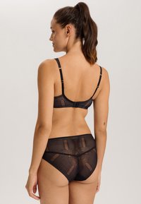 Black lace lingerie set featuring a geometric pattern with adjustable straps and hook closure on the back of the bra and brief.