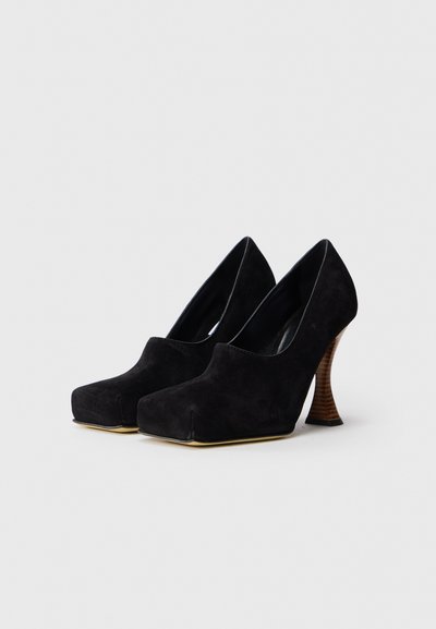 Pantofi negri din suede cu toc înalt, cu o platformă groasă și un toc din lemn texturat, curbat. Interior neted și design îndrăzneț cu vârf pătrat.
