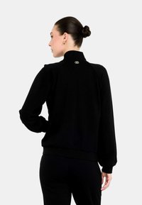 Felpa nera con collo alto e polsini a coste, caratterizzata da un piccolo logo dorato vicino al collo e da una vestibilità comoda.