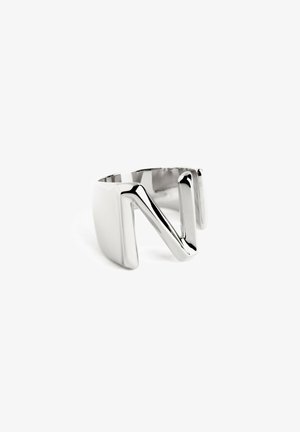Anillo de metal en tono plateado con un diseño abierto, cortes angulares, acabado liso y forma geométrica de "N".