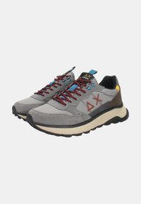 Sneaker grigie con una combinazione di tomaia in camoscio e rete, lacci rossi, accenti blu e suola chunky beige. Presentano un logo e occhielli.