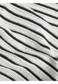 Tejido de punto con rayas horizontales en blanco y negro. El material es ligero y presenta una textura abierta, similar a encaje, con detalles de costura visibles.
