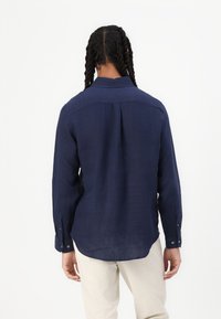 Camicia a maniche lunghe blu navy in tessuto leggero, con colletto classico, polsini abbottonati e una vestibilità rilassata con orlo curvo.