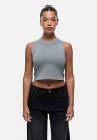 Grijze mouwloze crop top met een ronde halslijn, van gestructureerde stof, gecombineerd met hooggeselecteerde zwarte spijkerbroeken met gedetailleerde stiksels en zijzakken.