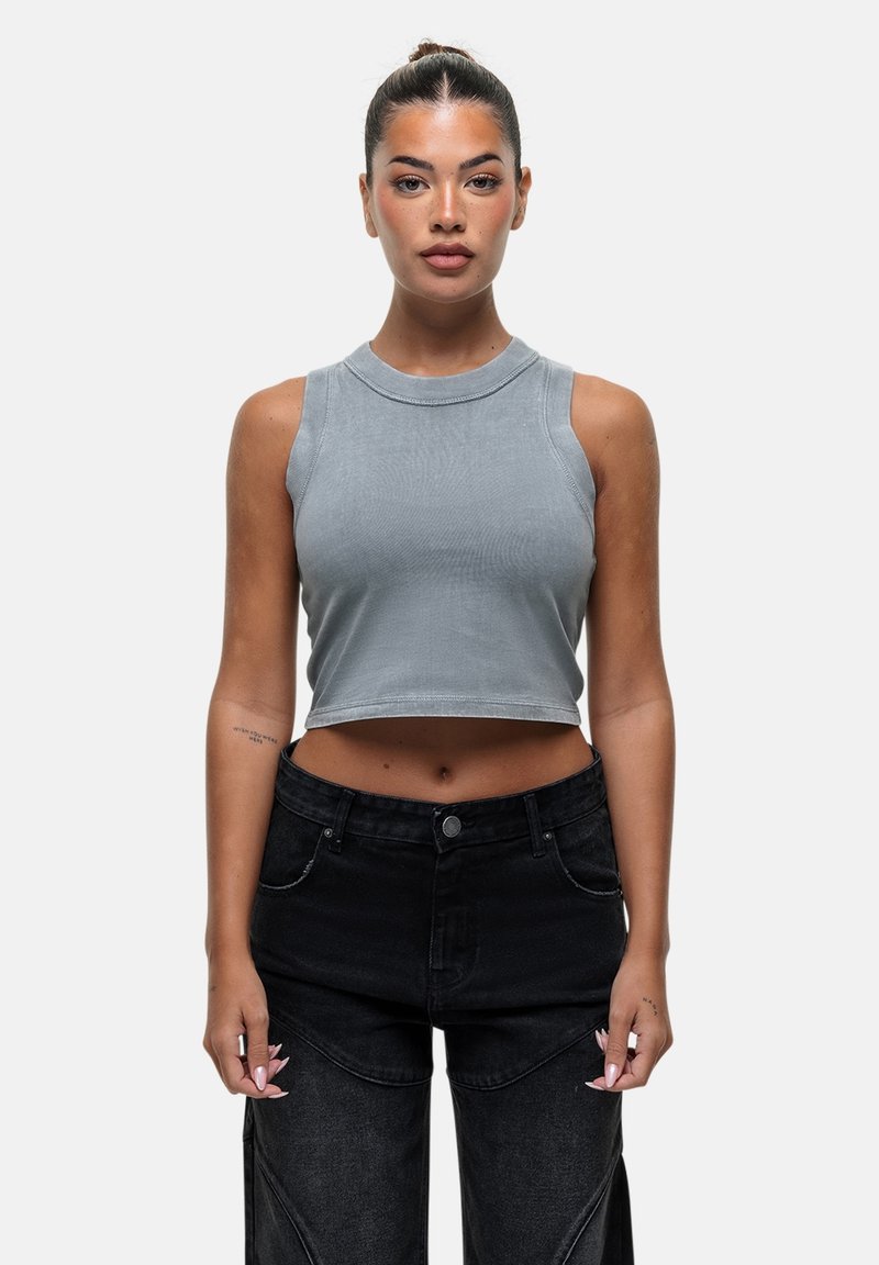 Grijze mouwloze crop top met een ronde halslijn, van gestructureerde stof, gecombineerd met hooggeselecteerde zwarte spijkerbroeken met gedetailleerde stiksels en zijzakken.