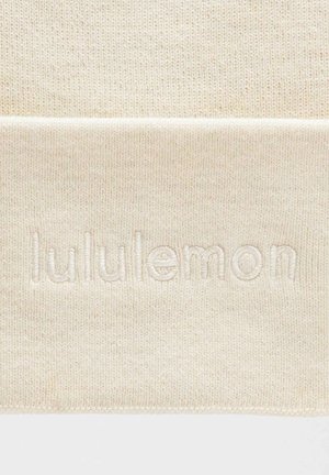Kreemivärvi kudum, mille keskosas on tõusnud, sama värvi esile toeva "lululemon" logo. Pehme tekstuur, ribakujulised servad.