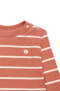 Pull en maille côtelée rayé en corail doux avec des rayures horizontales blanches ; il présente un petit badge décoratif au niveau du col et une fermeture à pression.