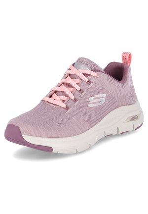 Zapatilla deportiva de color rosa claro con parte superior de tela texturizada, cordones rosas y suela blanca. Presenta un sutil logo y un tirador en el talón.