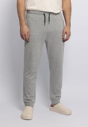 Gray cotton sweatpants with elastic waistband, drawstring, two side pockets, and ribbed cuffs. Paired with beige slip-on shoes.
