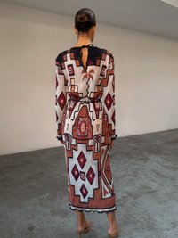 Robe multicolore à manches longues avec des motifs géométriques en bordeaux et blanc. Elle présente un col haut, un dos ouvert et une texture côtelée.